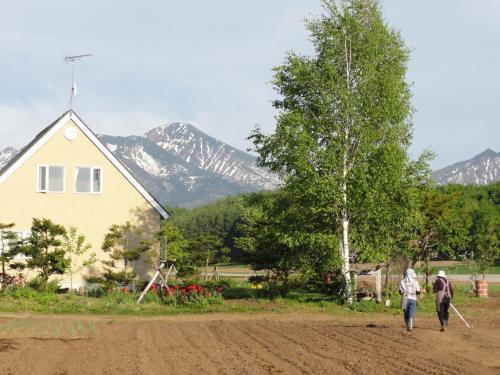 two people walking down a dirt road in front of a house at The Sanfurano in Kami-furano