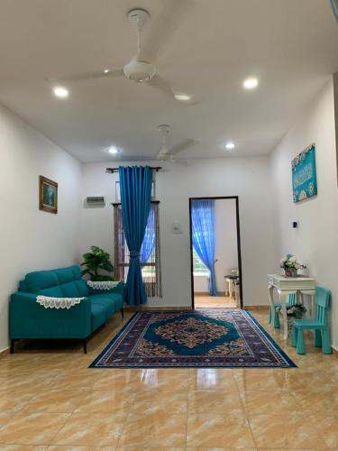 a living room with a blue couch and a mirror at Ma’wa Homestay in Kota Bharu