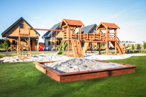 un parque infantil frente a una casa en Chic holiday homes for up to 6 people in Ustka, en Ustka