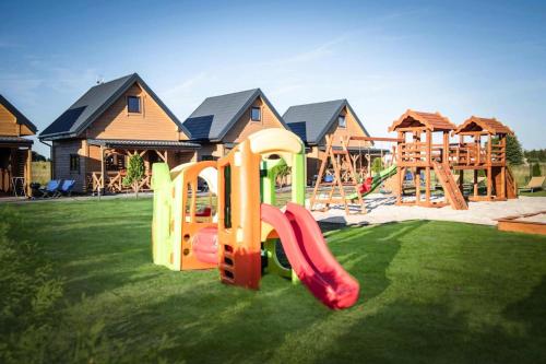 un patio con parque infantil con toboganes y equipo de juegos en Chic holiday homes for up to 6 people in Ustka, en Ustka