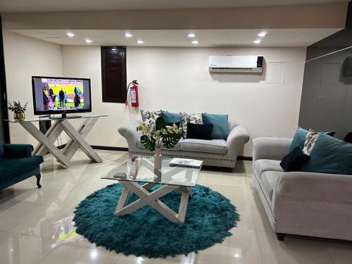 a living room with couches and a tv and a table at Hotel Francis in Culiacán