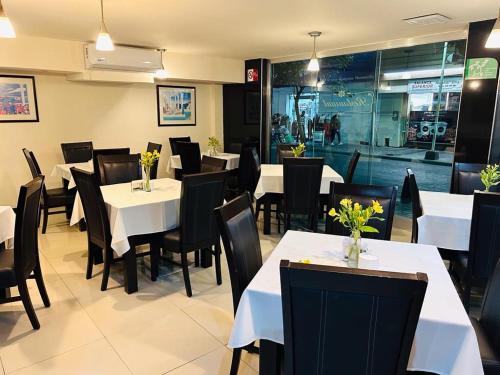 a dining room with white tables and black chairs at Hotel Francis in Culiacán