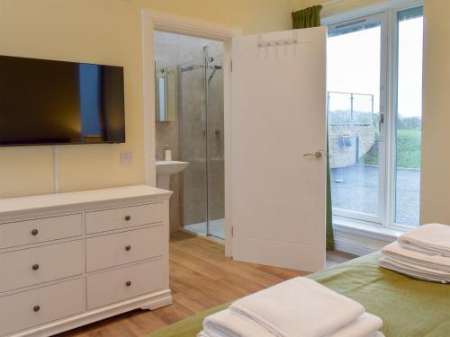 a bedroom with a shower and a dresser with a television at Falcon Cottage in Linlithgow