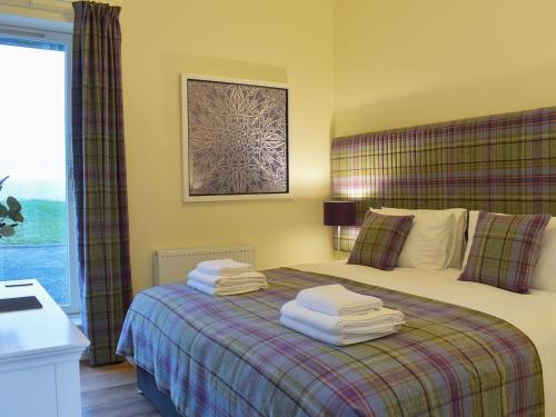 a bedroom with a bed with towels on it at Falcon Cottage in Linlithgow