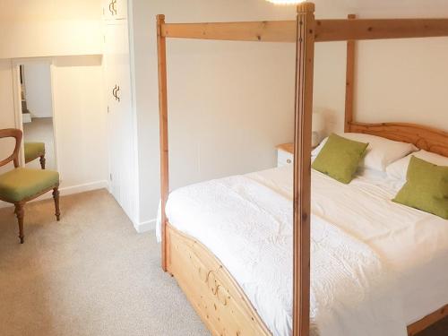 a bedroom with a four poster bed and a chair at Stable in Delabole