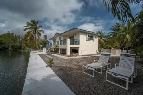 una casa con dos sillas junto a un cuerpo de agua en Boater's Dream House on the water 150' of Sea Wall, en Big Pine Key