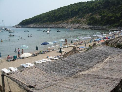 a group of people on a beach with umbrellas at Villa Pincevic in Lopud Island