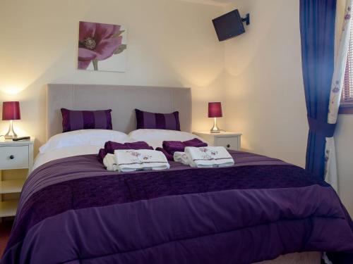a bedroom with a purple bed with two towels on it at Craigrossie Cottage in Auchterarder