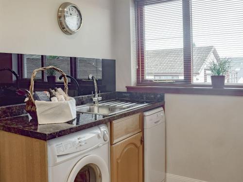 a kitchen with a sink and a washing machine at Craigrossie Cottage in Auchterarder