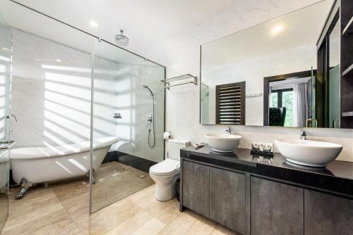 een badkamer met 2 wastafels, een bad en een toilet bij HAKO HOTEL JBCC in Johor Bahru