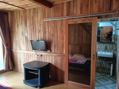 Zimmer mit einer Tür, einem TV und einem kleinen Tisch in der Unterkunft ADK Papandayan Homestay & Tour in Tjisurupan