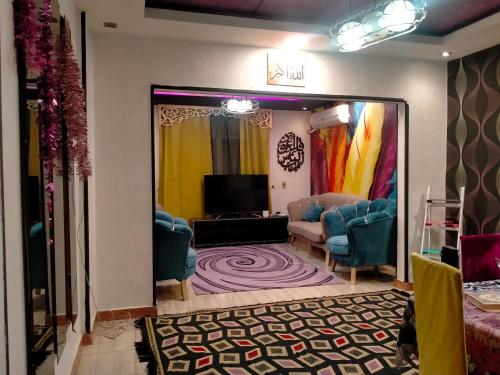 ein Wohnzimmer mit einem TV und blauen Stühlen in der Unterkunft ٢٨٠ شارع الملك فيصل الرئيسي برج النور in Kairo
