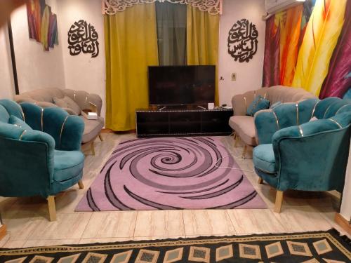 ein Wohnzimmer mit 2 blauen Stühlen und einem TV in der Unterkunft ٢٨٠ شارع الملك فيصل الرئيسي برج النور in Kairo
