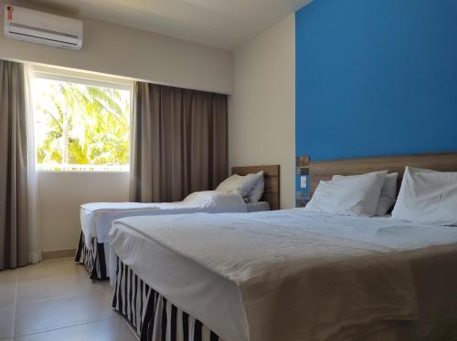 2 camas en una habitación de hotel con ventana en Ondas Praia Resort, en Porto Seguro