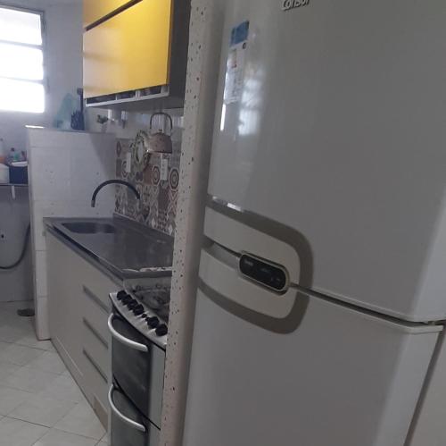 a white refrigerator in a kitchen with a sink at Apartamento pé na areia Praia do Gonzaguinha. in São Vicente