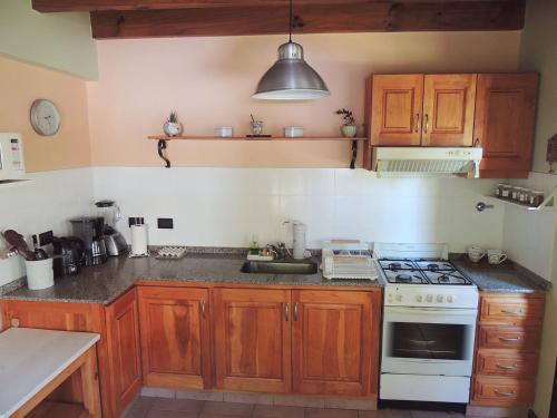 cocina con armarios de madera y horno con fogones en Allegra, casa de descanso en San Martín de los Andes