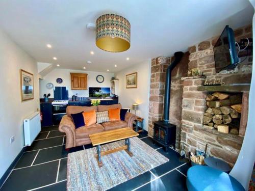 a living room with a couch and a stone fireplace at Stylish & cosy barn minutes from the Lake District in Penrith