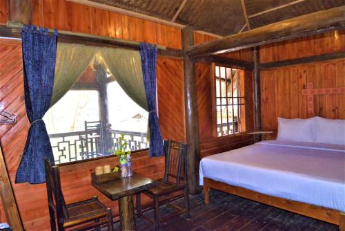 a bedroom with a bed and a table and a window at H'mong Eco House in Lao Cai