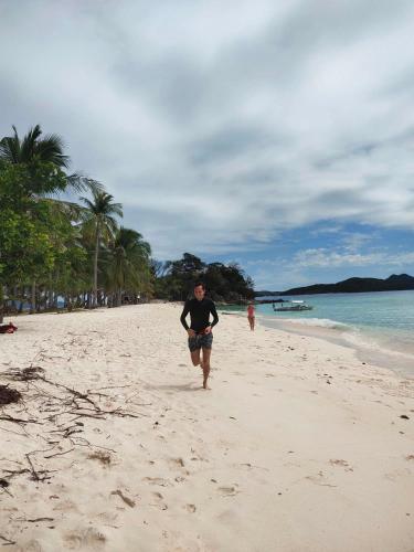 Un homme marche sur la plage dans l'établissement SUN'STAR TRAVEL AND TOURS AGENCY CORON PALAWAN, à Coron