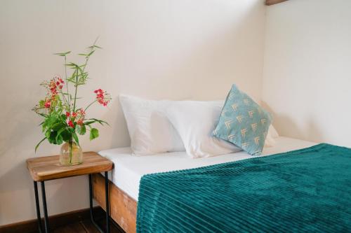 a bed with white sheets and a vase of flowers on a table at Hygge Siargao in General Luna