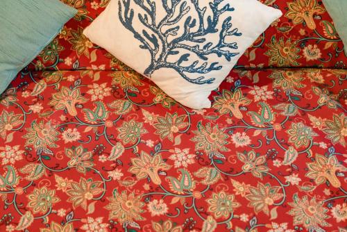 a bed with a red comforter and a pillow at Hygge Siargao in General Luna