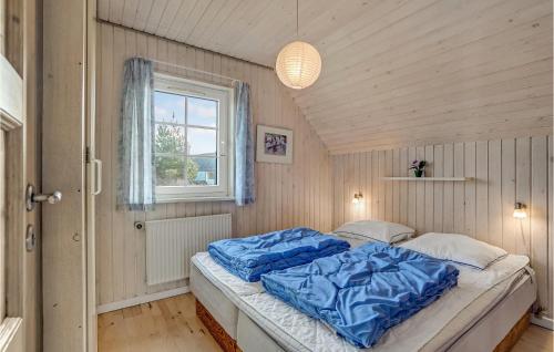KlegodにあるBeautiful Home In Ringkbing With 5 Bedrooms, Sauna And Indoor Swimming Poolのベッドルーム1室(青いシーツと窓付)