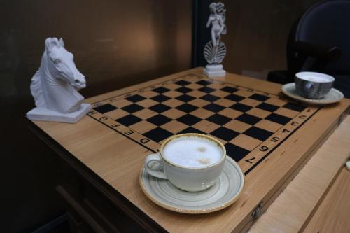 a chess board with a cup of coffee and a horse on a table at The Pearl Airport Hotel in Arnavutköy