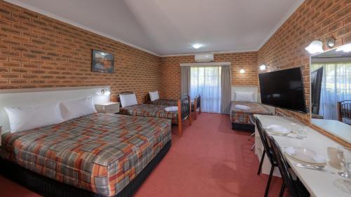 Glider City Motel Benalla في بينالا: غرفة فندق بسرير وتلفزيون