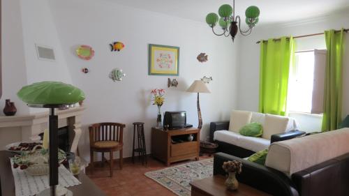 a living room with a couch and green curtains at Casa dos Peixes in Porto Covo