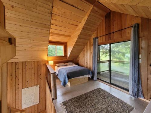 a bedroom in a log cabin with a bed and a window at Rustic cedar Cabin in Powell River