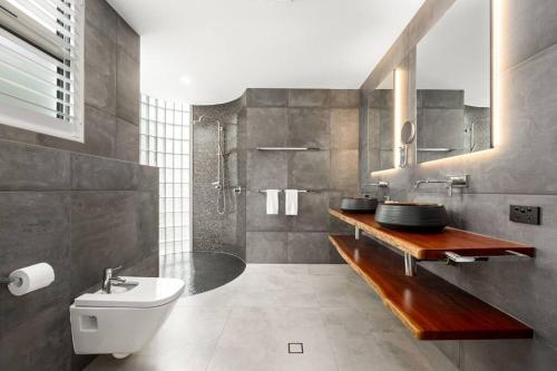 ein Bad mit einem Waschbecken, einem WC und einer Dusche in der Unterkunft Luxury Alex Beach Home in Alexandra Headland