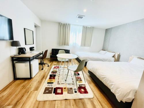 a room with two beds and a table and a desk at Megu fuji 2021 - Vacation STAY 74531v in Fujiyoshida