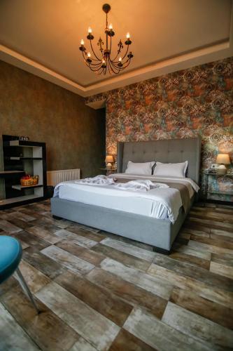a bedroom with a large bed and a chandelier at Panorama 360° Hotel in Tbilisi City