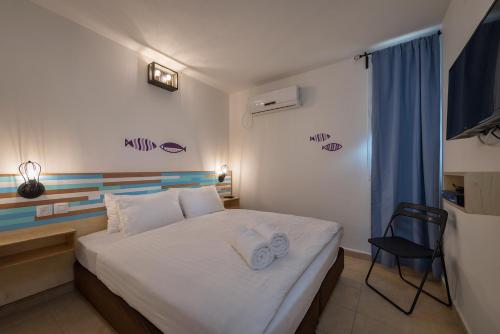 a bedroom with a bed and a chair in it at קיבוץ אילות - חדרי אירוח עם בריכה משותפת in Eilat