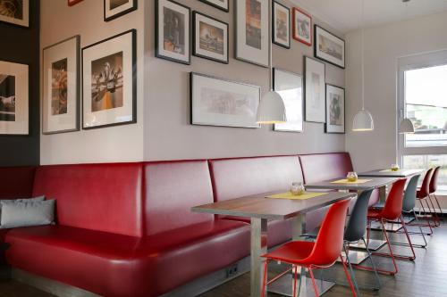 a restaurant with red booths and tables and pictures on the wall at Campanile Leipzig Halle Airport in Leipzig