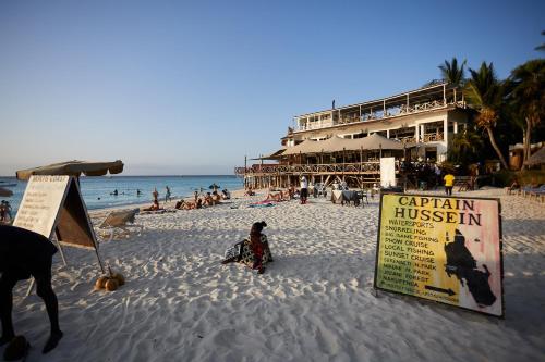 a beach with a sign in the sand and a building at Malika Nungwi Hotel in Nungwi