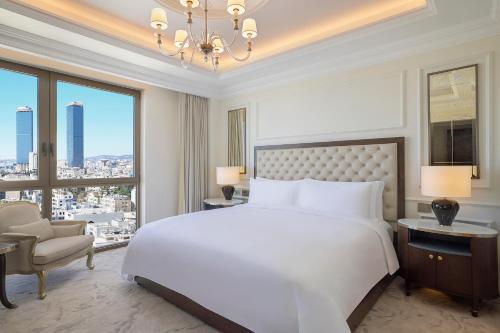 sypialnia z dużym białym łóżkiem i dużym oknem w obiekcie The Ritz-Carlton, Amman w mieście Amman