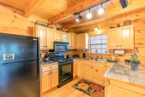 a kitchen with wooden cabinets and a black refrigerator at Moonshine Ridge Cabin with Hot Tub and Fire Pit in Pigeon Forge