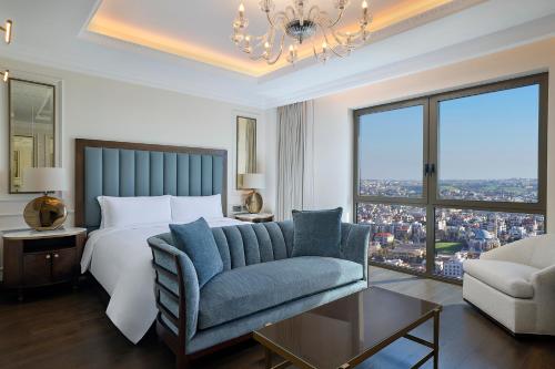 a bedroom with a bed and a couch and a chandelier at The Ritz-Carlton, Amman in Amman