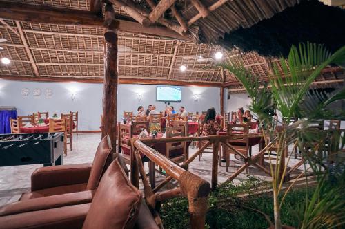 a group of people sitting in a restaurant at Malika Nungwi Hotel in Nungwi