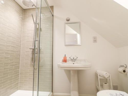 a white bathroom with a sink and a shower at The Bath House in Blockley