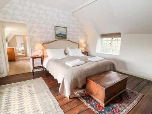 a bedroom with a large bed and a table at Holly Cottage in Minster Lovell