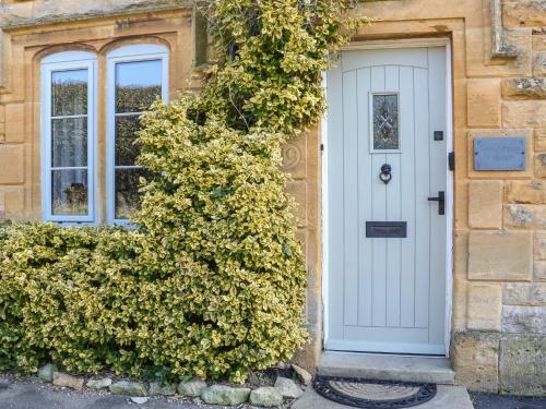 a house with a white door and two windows at Green Pump Cottage in Blockley