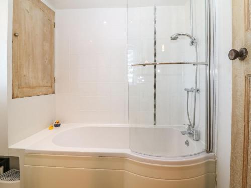 a bathroom with a tub with a glass shower at Green Pump Cottage in Blockley