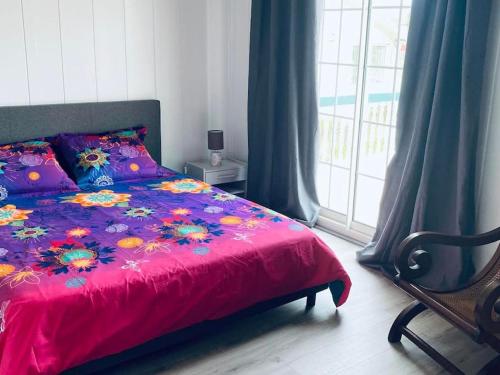 a bedroom with a bed with a pink blanket and a window at Maison a Bourg- Murat proche de la cité du volcan in La Plaine des Cafres