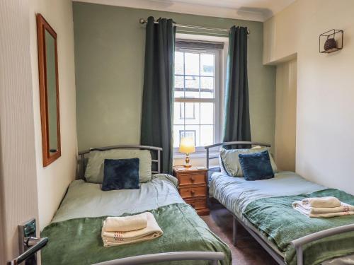 two twin beds in a room with a window at The Oaks Cottage in Penrith