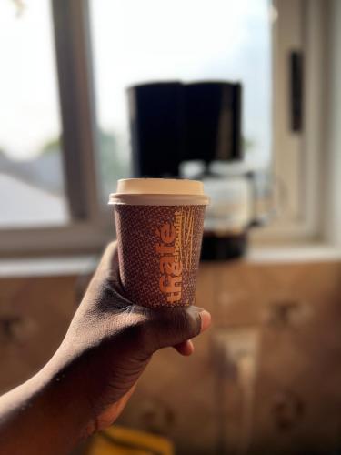 a person holding a coffee cup in their hand at Bel appartement avec petit balcon sympa in Porto-Novo