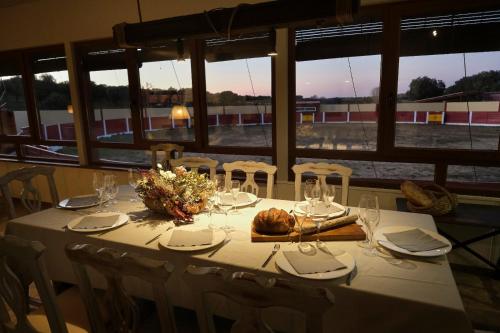 una mesa con un mantel blanco y sillas con vistas a un tren en CASA RURAL "LA MAZA" entre encinas y dehesas en Terradillos