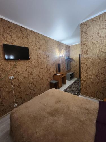 1 dormitorio con 1 cama y TV en la pared en Оазис en Almaty