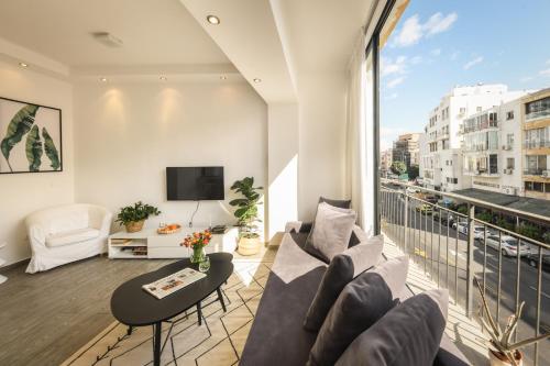 uma sala de estar com um sofá e uma televisão em Charming 1 BR Apt w Sliding Window in Tel Aviv by Sea N' Rent em Tel Aviv